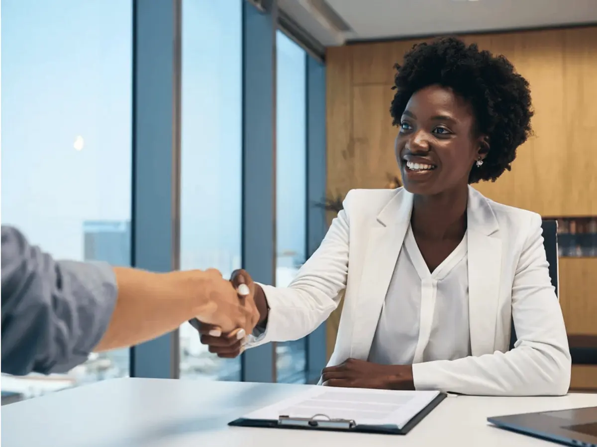 An adviser shakes hands with a client across a desk