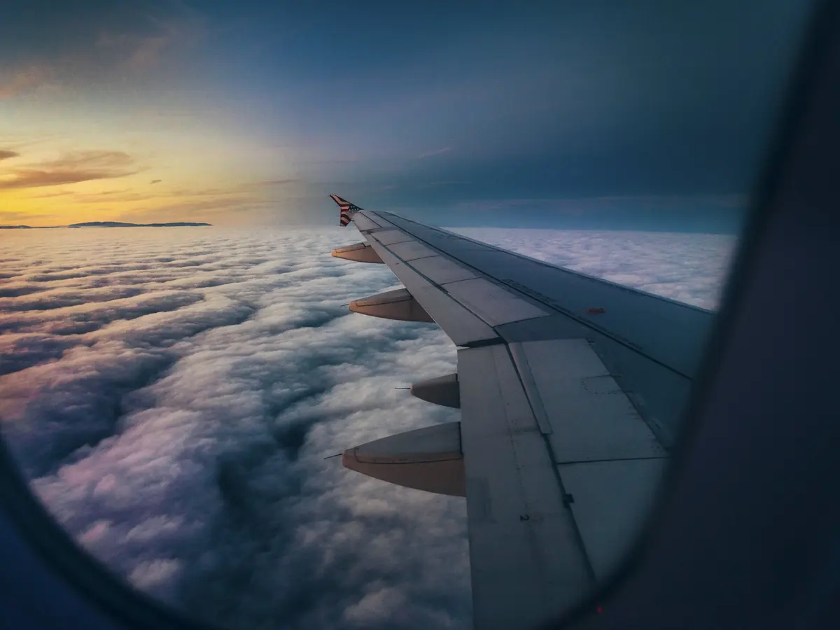 Clouds below an aircraft wing at sunrise