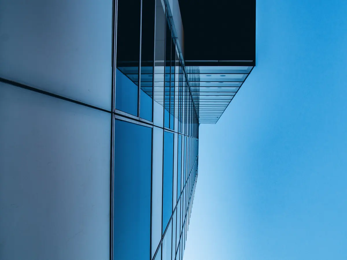 A glass office tower against a blue sky