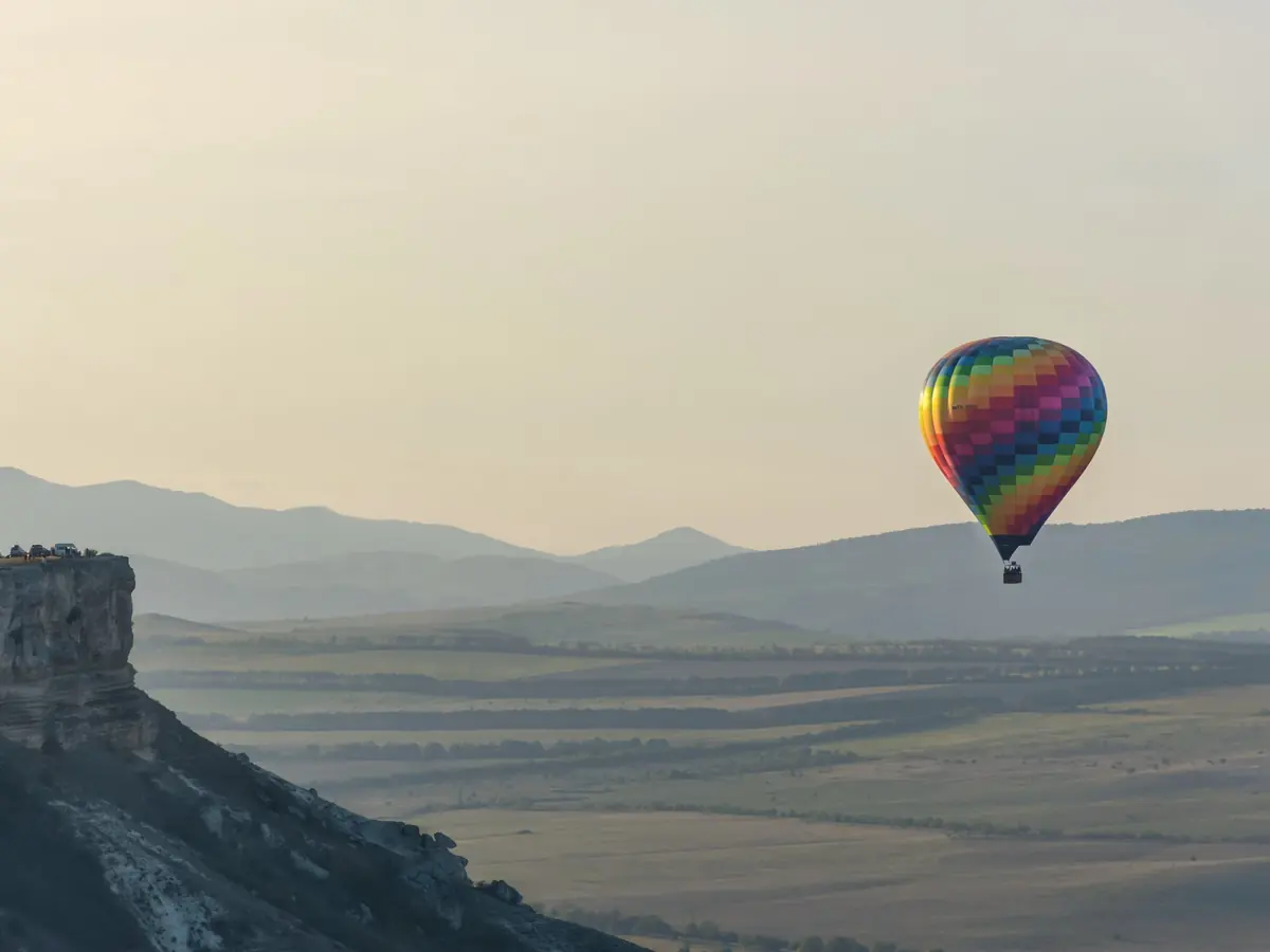 A hot air balloon over a valley at sunrise