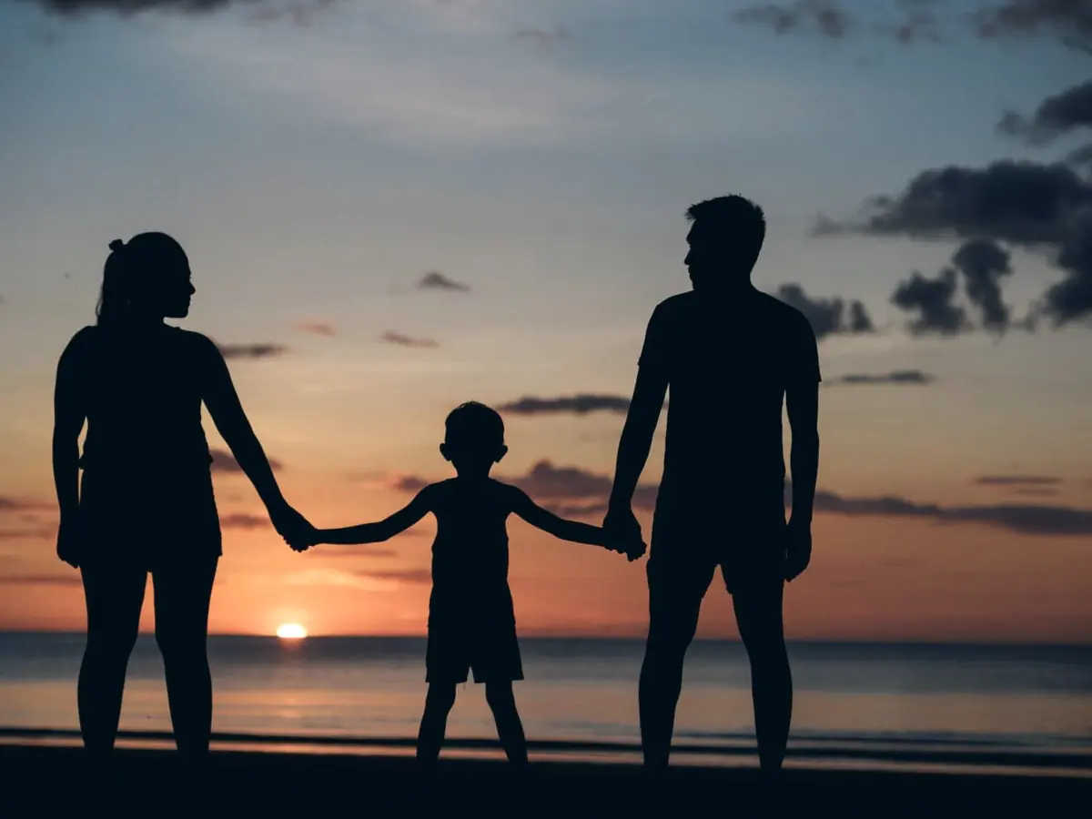 A family walks hand in hand along a beach at sunset