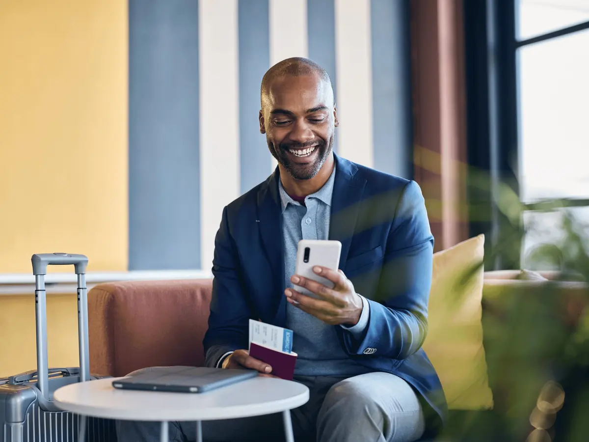 A client smiles at his phone in an airport lounge