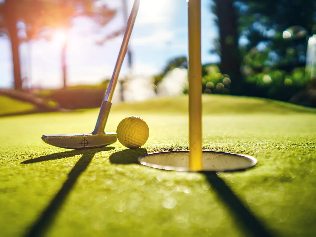 A golf ball beside the hole on a sunlit green